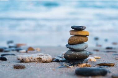 Çakıl taşları deniz kıyısındaki volkanik bir kayanın üzerine yığılır. Zen konsepti. Boşluğu kopyala.