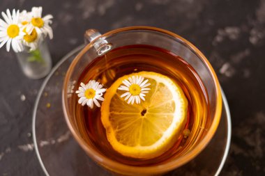 Limonlu bir fincan çiçek çayı ve papatya çayı. Siyah bulanık arkaplan. Yakın çekim.