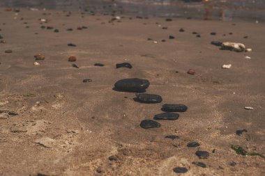 Siyah düz zen taşları bir deniz kumsalının kumlarında yatıyor..