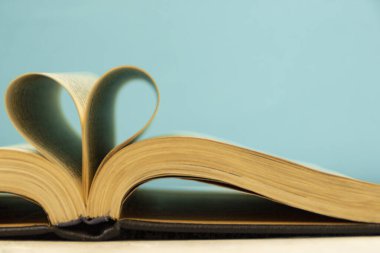 Kitabın sayfaları kalp şeklinde kıvrımlıdır. Mavi arka planda açılan bir kitap. Okul temasına geri dönelim. Bibliyofil.