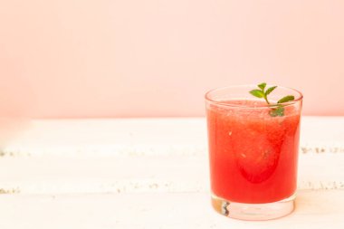 Beyaz arka planda cam bardakta yeşil naneli lezzetli kırmızı karpuz suyu. Uzayı kopyala Yaz yemekleri konsepti