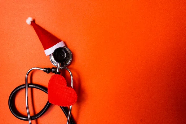 Christmas medical flatly. Medical Christmas banner with stethoscope, Santa hat, heart on red background. Copyspace. New Year\'s medicine is categorical. Christmas medical categorically