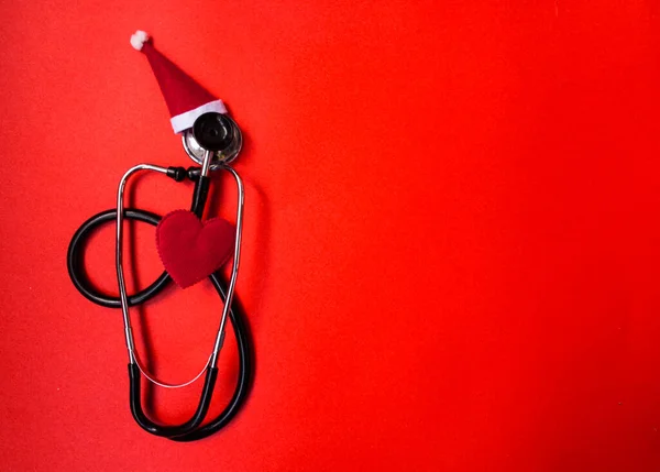 Christmas medical flatly. Medical Christmas banner with stethoscope, Santa hat, heart on red background. Copyspace. New Year\'s medicine is categorical. Christmas medical categorically