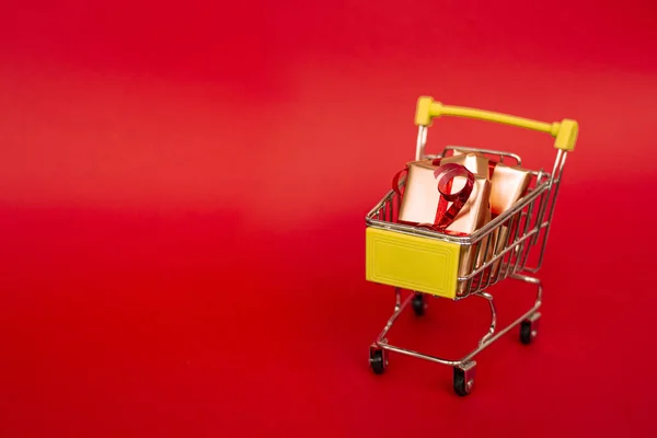 Koszyk Spożywczy Złotymi Pudełkami Czerwoną Wstążką Czerwonym Tle Baner Miejsca — Zdjęcie stockowe