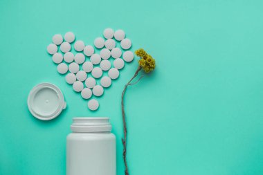 İlaçlar beyaz, yuvarlak kalp üzerinde turkuaz arka plan izole hap şeklinde..