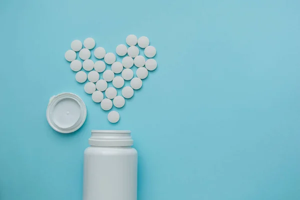 Medicamentos blancos, píldoras redondas en forma de corazón aisladas sobre fondo azul . — Foto de Stock