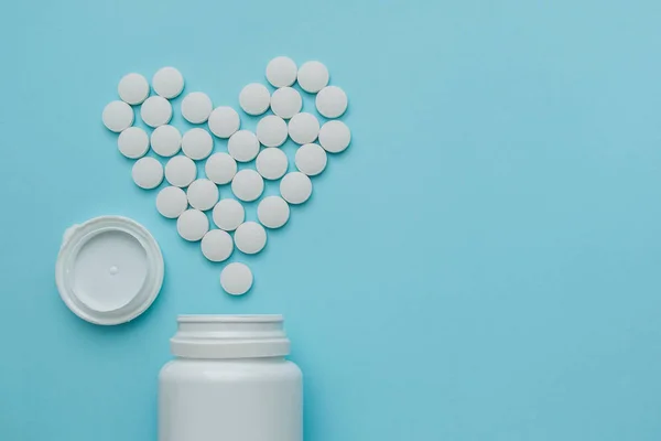 Medicamentos blancos, píldoras redondas en forma de corazón aisladas sobre fondo azul . —  Fotos de Stock