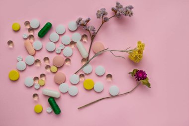 çok renkli hapları pembe bir arka plan üzerinde dağınık. şifalı otlar.