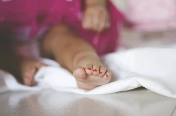 Baby girl sitting down on the floor in a pink skirt. Close up feet. Baby girl sitting down on the floor in a pink skirt. Close up of her feet.