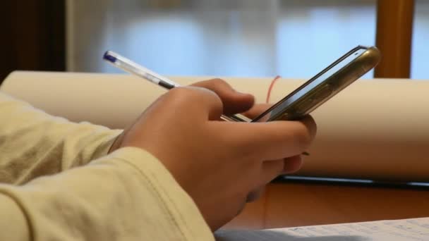 Pojke Med Smartphone Medan Gör Skolan Läxor — Stockvideo