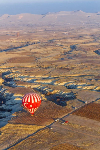 Red Hot-Air Balloon with Crescent Star Landing with Landscape of Cappadocia, in Central Turkey