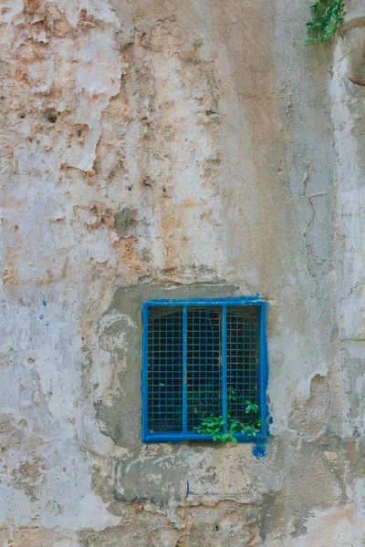 Blue metal window on old textured white wall of the sassi of Matera, Italy
