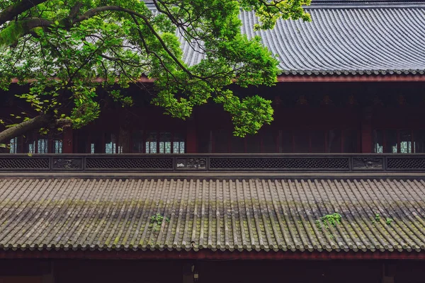 stock image Architectural details of traditional Chinese building, with black tiled rooftop under trees, in Lingyin Temple, Hangzhou, China