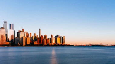 New Jersey, New York City, Amerika Birleşik Devletleri her gün batımında, mavi gökyüzü altında Manhattan Hudson Nehri üzerinde şehrin manzarası görünümünü bakıldığında