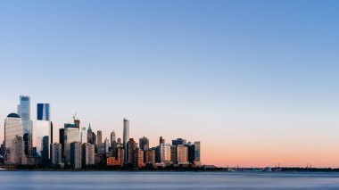 New Jersey, New York City, Amerika Birleşik Devletleri her gün batımında, mavi gökyüzü altında Manhattan Hudson Nehri üzerinde şehrin manzarası görünümünü bakıldığında
