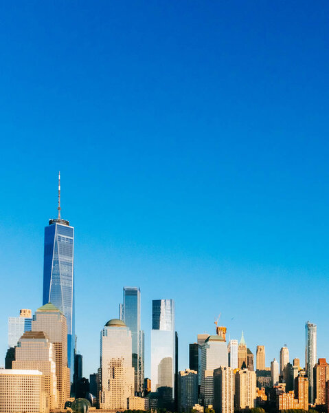 View of the skyline of downtown Manhattan under blue sky, at sunset, viewed from New Jersey, in New York City, USA