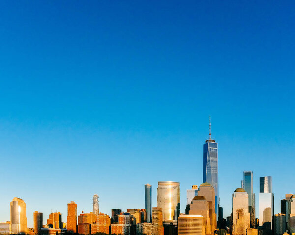 View of the skyline of downtown Manhattan under blue sky, at sunset, viewed from New Jersey, in New York City, USA