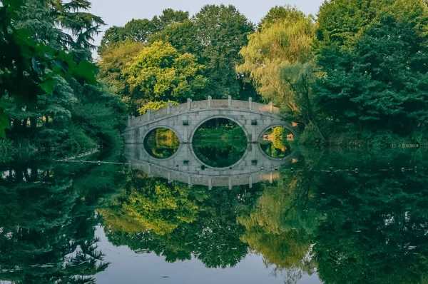 View of traditional Chinese stone bridge and its reflection in the lake near West Lake, Hangzhou, China