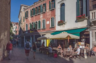 Venedik binaları ve sokaklarının yanındaki kafede oturan insanlar