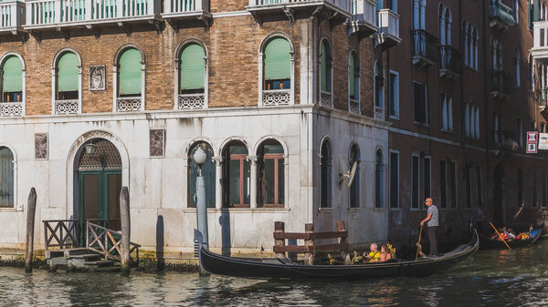 Venice, Italy - June 6, 2017: Gondola traveling on the canal along Venetian buildings