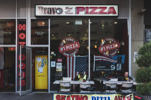Lokalbefolkningen äter pizza i sittplatsen framför en lokal pizz — Stockfoto