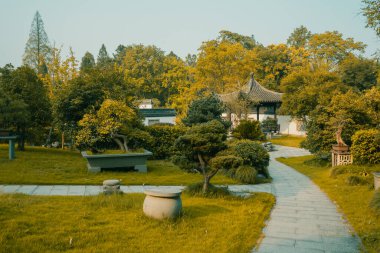 Hangzhou, Zhejiang, Çin 'deki Hangzhou Botanik Bahçesi' nde ağaçlar ve bahçeler arasındaki patika.
