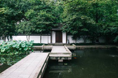 Çin 'in Hangzhou kentindeki Batı Gölü manzaralı bir bölgede geleneksel bir Çin bahçesinde göletin üzerinde köprü.