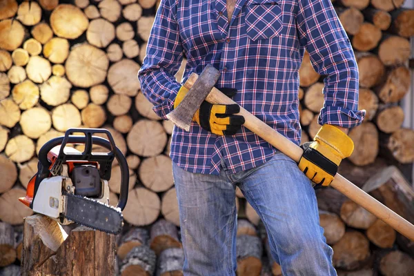 The worker works with a chainsaw. Chainsaw close up. Woodcutter saws tree with chainsaw on sawmill. Chainsaw in action cutting wood. Man cutting wood with saw, dust and movements.