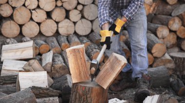 Endüstriyel balta tutan adam. Balta elinde. Güçlü bir adam elinde testereler ve yakacak odunların arka planına karşı bir balta tutar. Elinde balta olan güçlü bir oduncu. Elektrikli testereyi kapat..