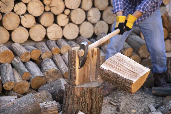 Man holding an industrial ax. Ax in hand. A strong man holds an ax in his hands against the background of chainsaws and firewood. Strong man lumberjack with an ax in his hand. Chainsaw close up.