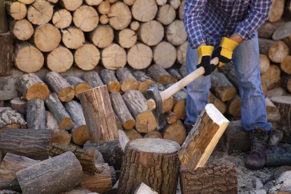 Man holding an industrial ax. Ax in hand. A strong man holds an ax in his hands against the background of chainsaws and firewood. Strong man lumberjack with an ax in his hand. Chainsaw close up.