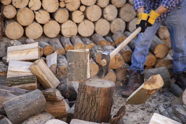 Man holding an industrial ax. Ax in hand. A strong man holds an ax in his hands against the background of chainsaws and firewood. Strong man lumberjack with an ax in his hand. Chainsaw close up.