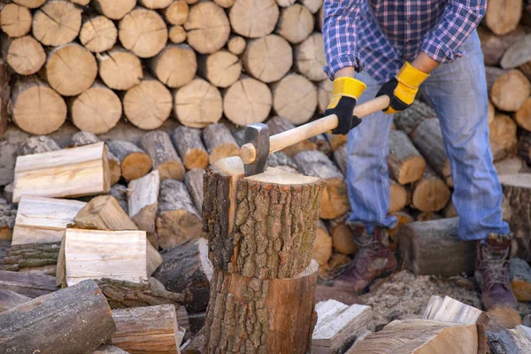 Man holding an industrial ax. Ax in hand. A strong man holds an ax in his hands against the background of chainsaws and firewood. Strong man lumberjack with an ax in his hand. Chainsaw close up.