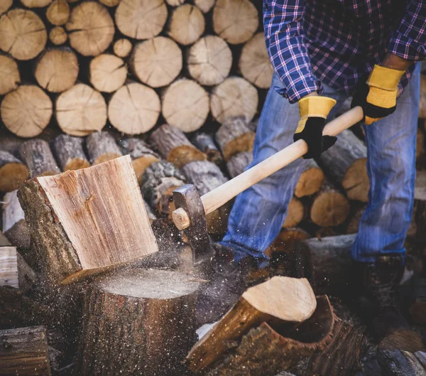 Man holding an industrial ax. Ax in hand. A strong man holds an ax in his hands against the background of chainsaws and firewood. Strong man lumberjack with an ax in his hand. Chainsaw close up.