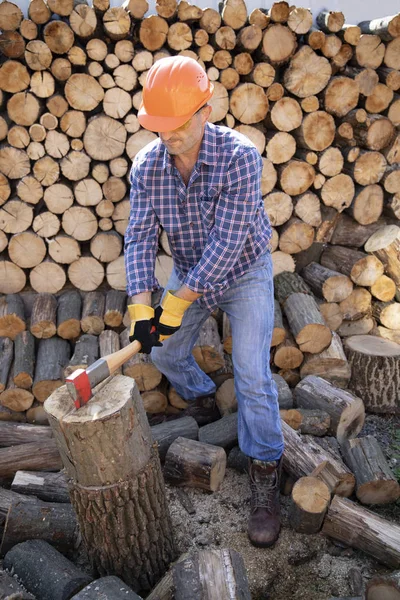 AX in de hand. Man met een industriële bijl. Een sterke man houdt een bijl in zijn handen tegen de achtergrond van brandhout. Sterke man houthakker met een bijl in zijn hand. — Stockfoto