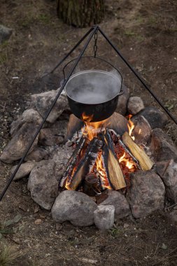 Bir ateş üzerinde pişirme. Balık çorbası bir yanıyor. Yiyecek bir kazan bir yanıyor. Gıda açık havada. Açık havada yemek. Kazan üzerinde doğada yemek.