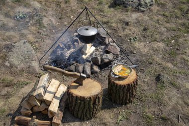 Bir ateş üzerinde pişirme. Balık çorbası bir yanıyor. Yiyecek bir kazan bir yanıyor. Gıda açık havada. Açık havada yemek. Kazan üzerinde doğada yemek.
