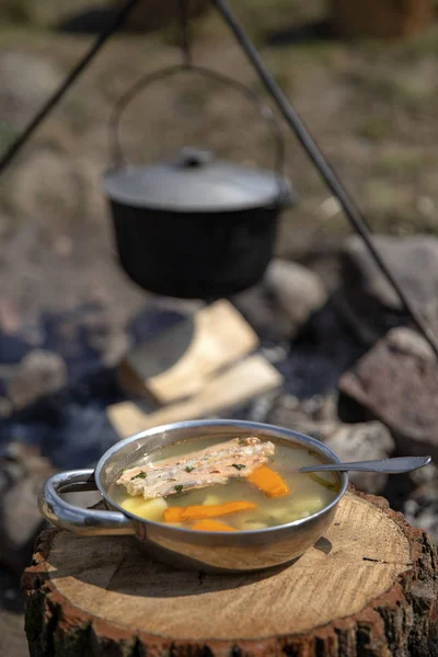 Cooking on a fire. Fish soup on a fire. Food in a cauldron on a fire. Food outdoors. Cooking outdoors. Cooking in nature on the cauldron.