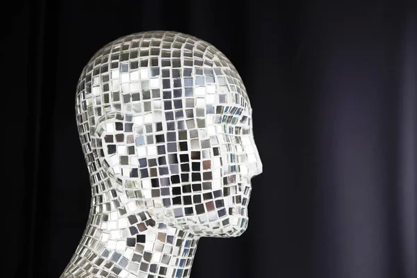 Mannequin head. Mannequin covered with slices of a mirror on a black background.