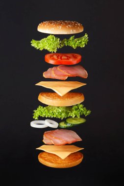 Uçan hamburger malzemeleri. Siyah zemin üzerinde uçan hamburgerler olan lezzetli hamburgerler. .