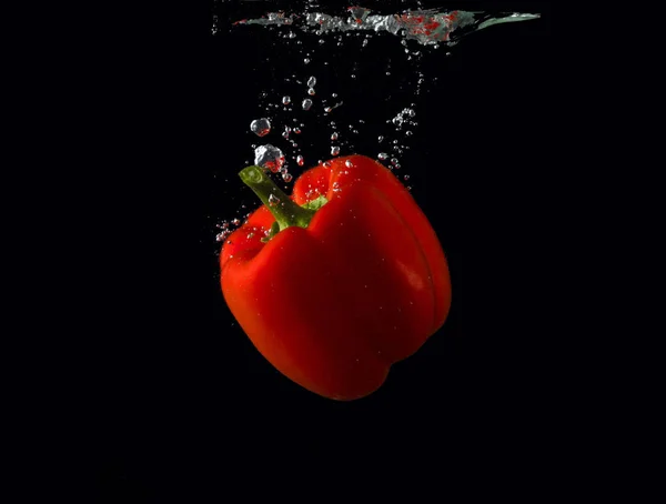 Pimiento rojo cayendo en el agua con salpicadura sobre fondo negro, pimentón, detener la fotografía en movimiento. Pimienta roja . —  Fotos de Stock