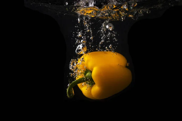 Poivron jaune tombant dans l'eau avec éclaboussure sur fond noir, paprika, photographie stop motion. Poivron jaune . — Photo