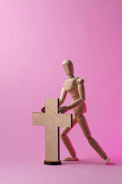 Ξύλινα άνθρωπος. Ένα ξύλινο άνθρωπος κατέχει ένα σταυρό. Σταυρός. Σταυρός στο χέρι. — Φωτογραφία Αρχείου