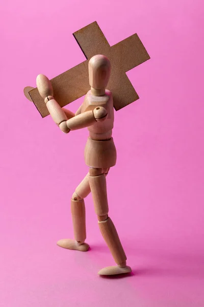Ξύλινα άνθρωπος. Ένα ξύλινο άνθρωπος κατέχει ένα σταυρό. Σταυρός. Σταυρός στο χέρι. — Φωτογραφία Αρχείου