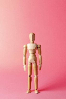 Pembe arka planda tahta bir manken. Tahta adam. Ahşap manken.