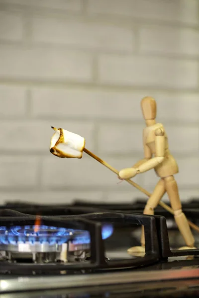 Wooden mannequin preparing marshmallows on fire. Cook marshmallo — Stock Photo, Image