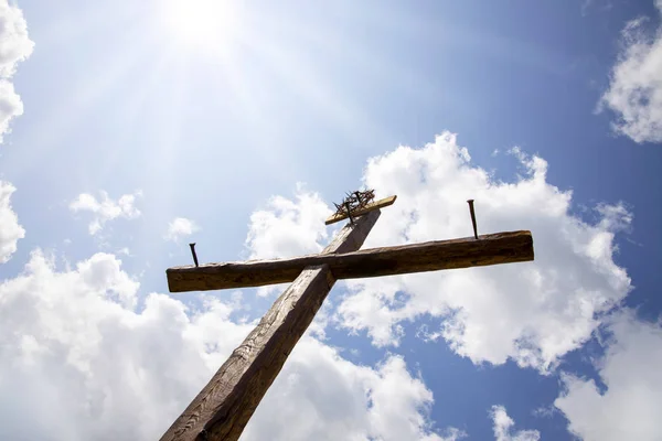 The Cross with bright sun and clouds in the background. Wood cro