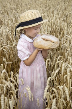 Küçük kız elinde yuvarlak ekmek tutuyor. Elleri büyük ekmek tutuyor. Fırın