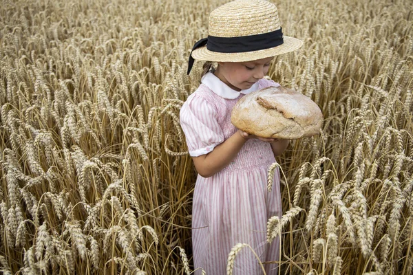 Liten flicka som håller runt bröd. Händer som håller stort bröd. Bageri — Stockfoto