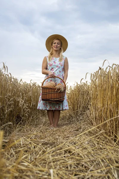 Uma mulher segura uma cesta com pão nas mãos. Mulher bonita em — Fotografia de Stock
